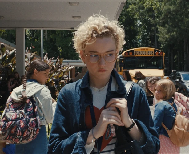 Julia Garner as a student outside a school, with a memorial for "BOOK STRONG" visible in the background.