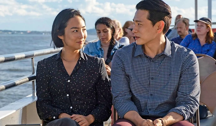 Greta Lee and Teo Yoo from "Past Lives" sitting on a boat.