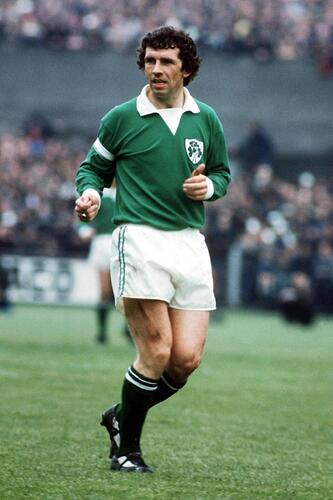 An Irish soccer player in a green jersey, white shorts, and green socks with white stripes.