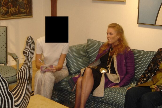 A woman sitting on a sofa looking on. Next to her, another woman is sitting, but her face has been redacted.