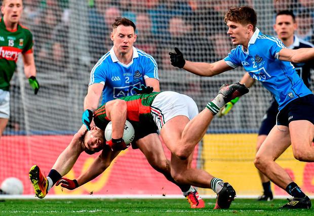 Mayo’s Aidan O’Shea falls to the ground under pressure from Dublin duo Phily McMahon and Mick Fitzsimons. Photo: Paul Mohan/Sportsfile