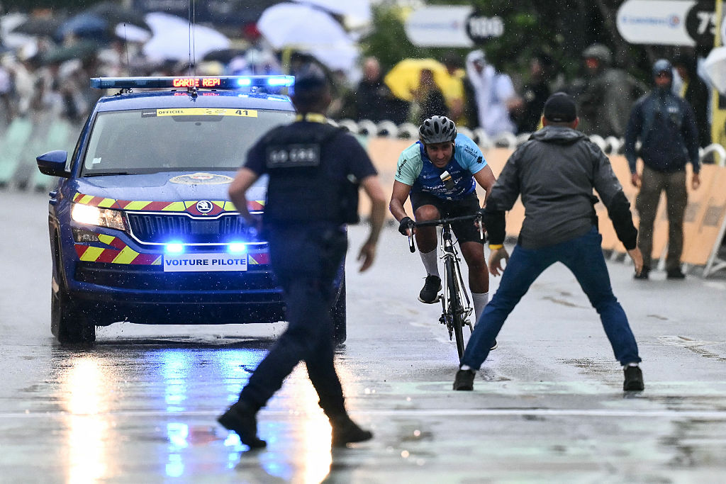 A French Republican Security Corps (CRS - Compagnies Republicaines de Securite) officer and a Tour de France staff member prepare to intercept an individual attempting to cycle across the finish line minutes before the final sprint of the 112th edition of the Tour de France cycling race, 160.4 km between Bollene and Valence, southern France, on July 23, 2025. (Photo by Marco BERTORELLO / AFP)